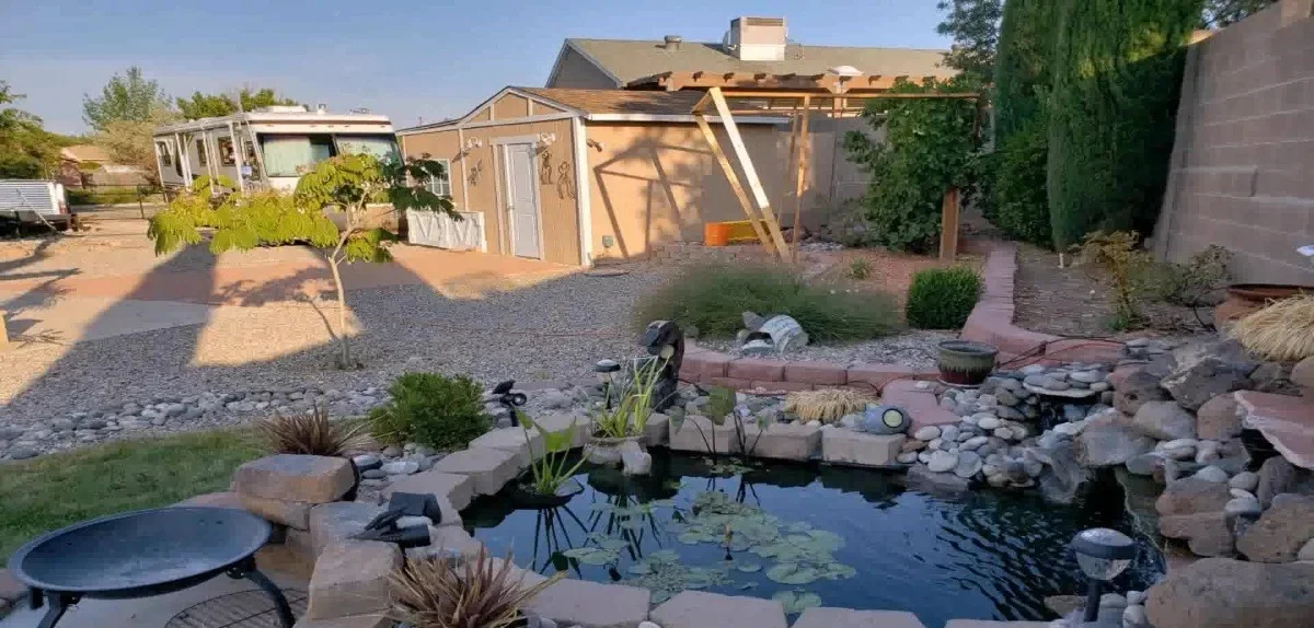 Backyard pond water feature with river rock and a fire pit seating area